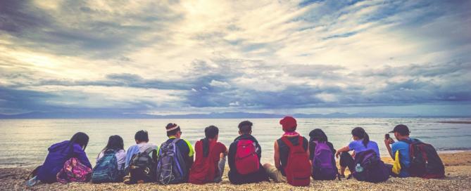 A group of young people sitting by a lake