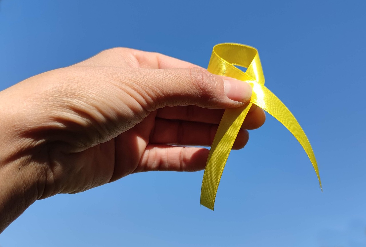 Hand holding yellow ribbon