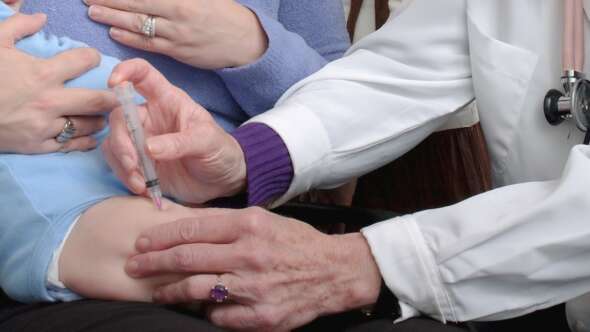 Doctor giving baby vaccination in leg