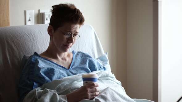 Woman sitting in hospital bed with a cup of coffee