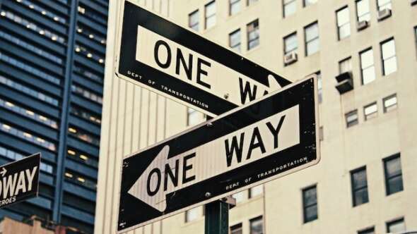 Two street "One Way" signs pointing in opposite directions