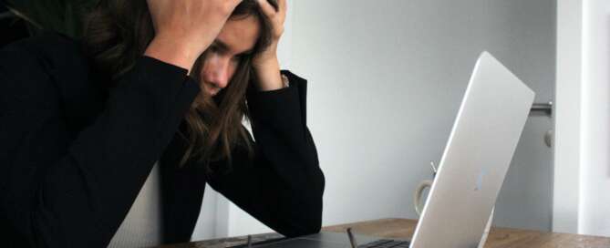 teenager stressed and holding head looking at laptop screen