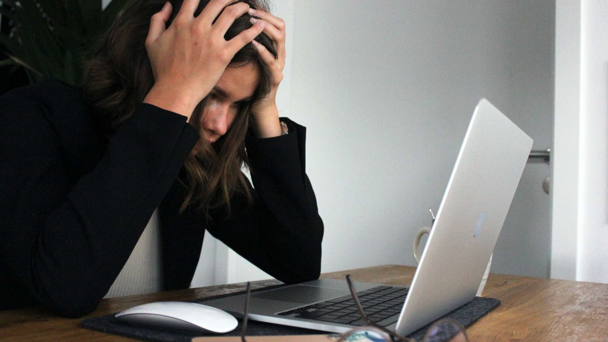 teenager stressed and holding head looking at laptop screen
