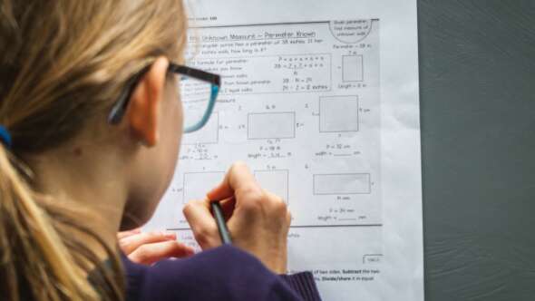 Young girl with blue reading glasses completing math homework