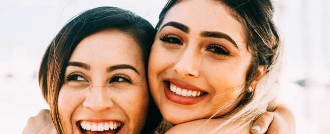 two female friends hugging each other with big smiles