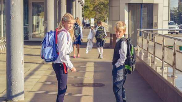 Two school students walking to school on a sunny day