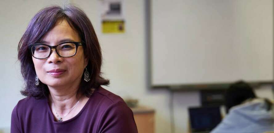 close up shot of teacher with student sitting at desk in the background
