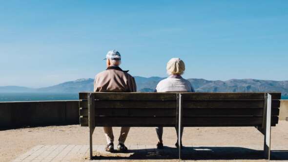 Older couple sitting side-by-side looking toward the sky