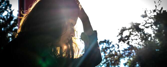 Girl wearing green sweater hand on her head looking down in disappointment