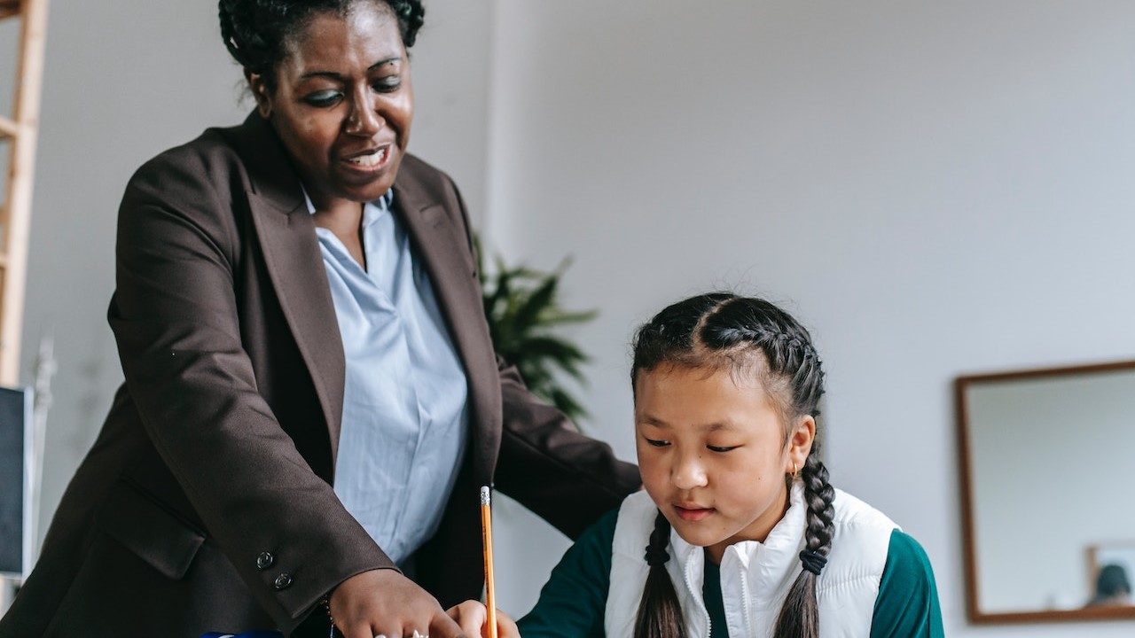 teacher supervising and assisting student in classroom