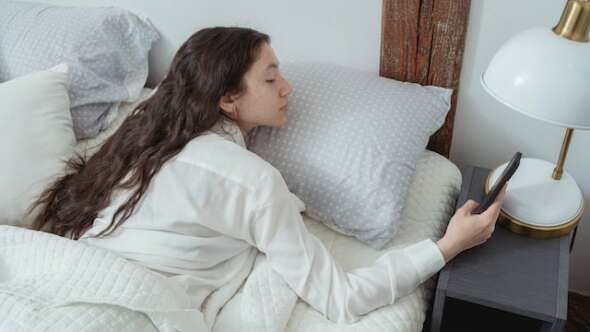woman in bed checking phone