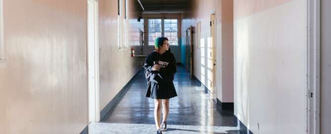 Girl with colourful short hair walking through school hallway looking anxious