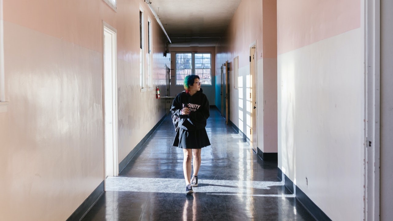 Girl with colourful short hair walking through school hallway looking anxious